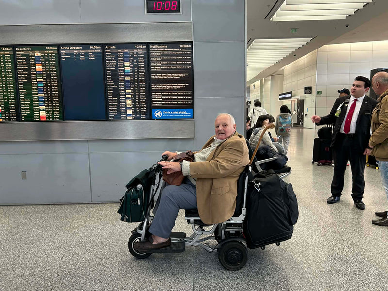 A customer riding the folding scooter through an airport terminal with their luggage